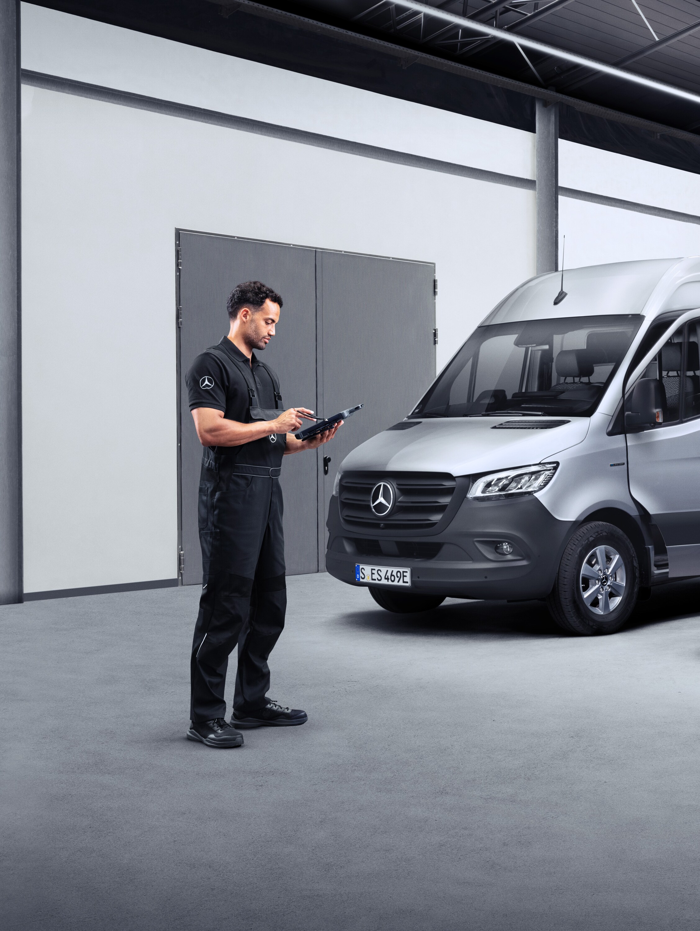 En tekniker framför två eldrivna transportbilar på en surfplatta