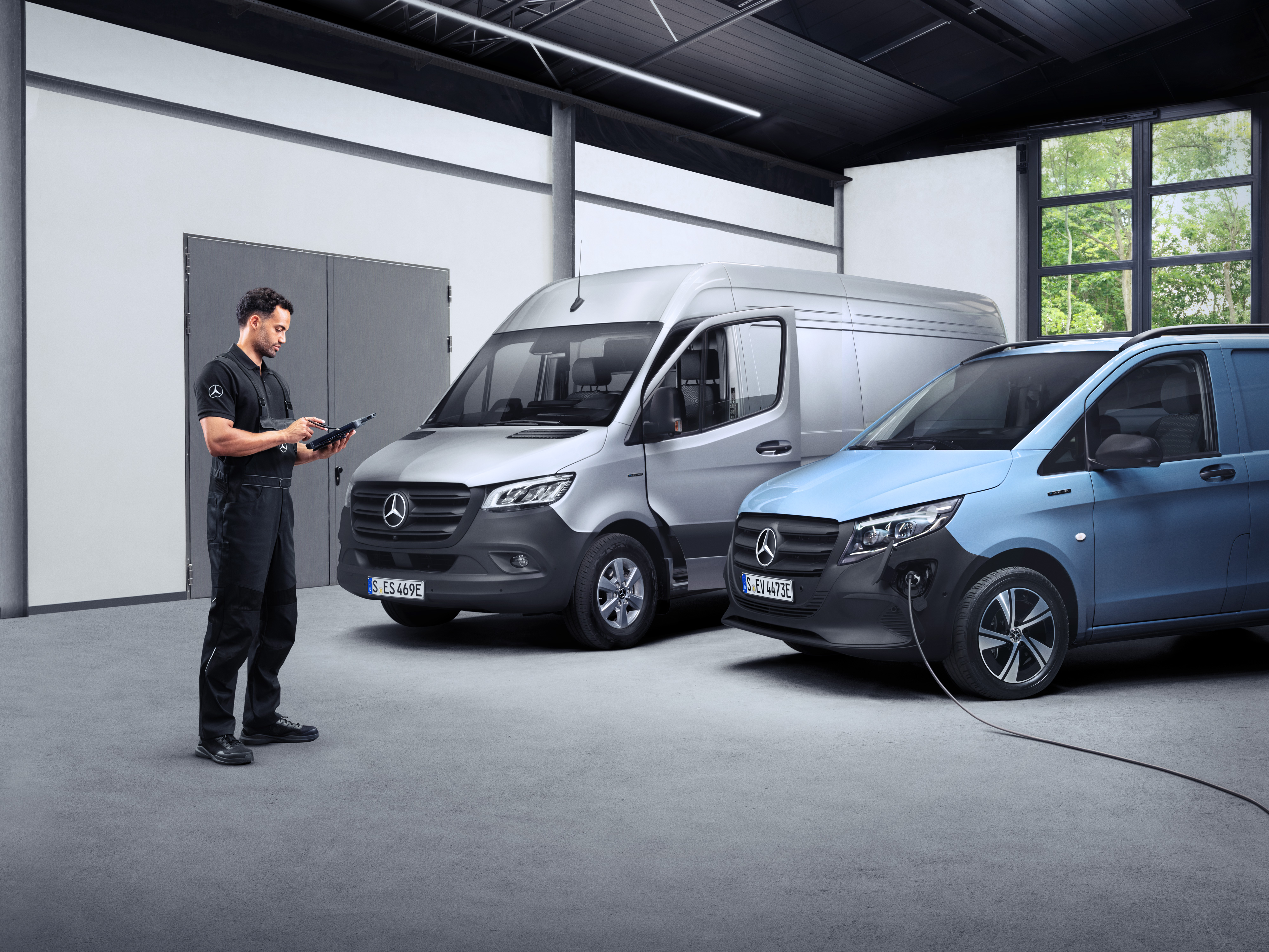 Mercedes-Benz | Van ServiceCare En tekniker framför två eldrivna transportbilar på en surfplatta.