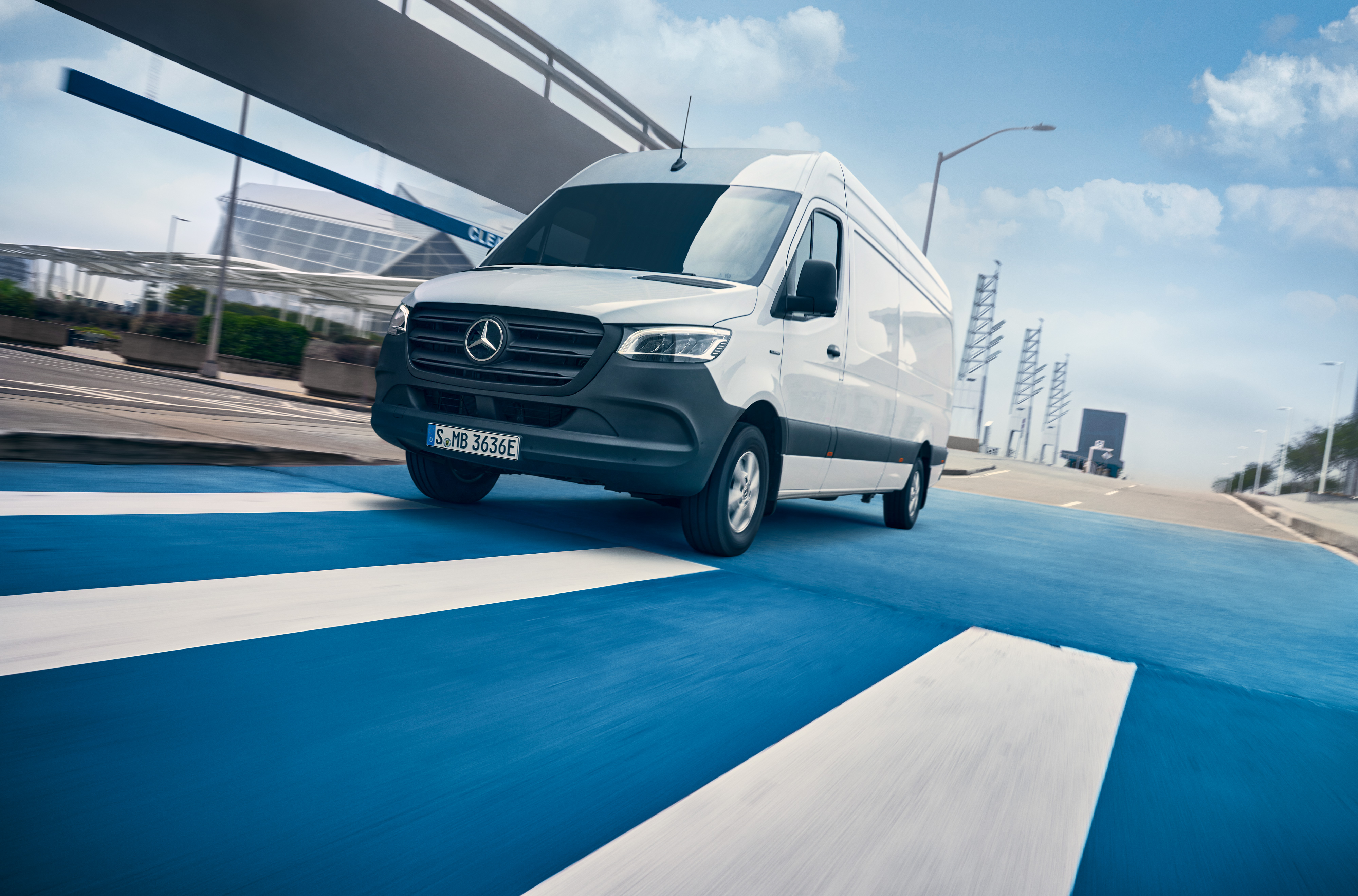 Mercedes-Benz | Van ServiceCare | Servicepaket En vit Mercedes-Benz Sprinter kör på en väg genom en stad.
