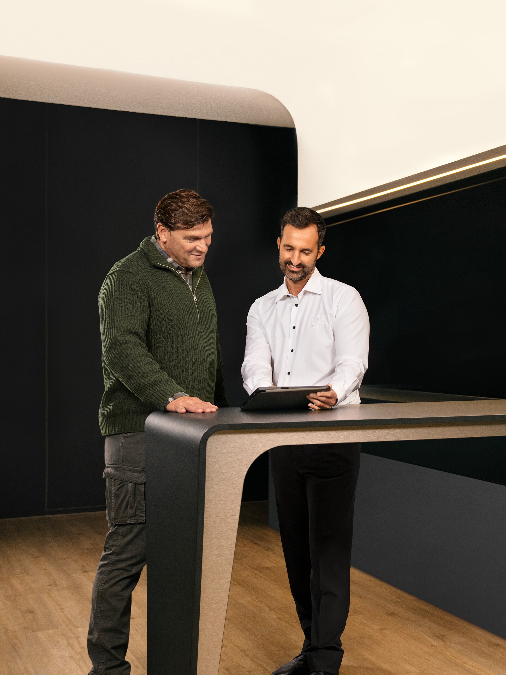 Två män diskuterar service för nkommersiella fordon från Mercedes-Benz över en surfplatta.