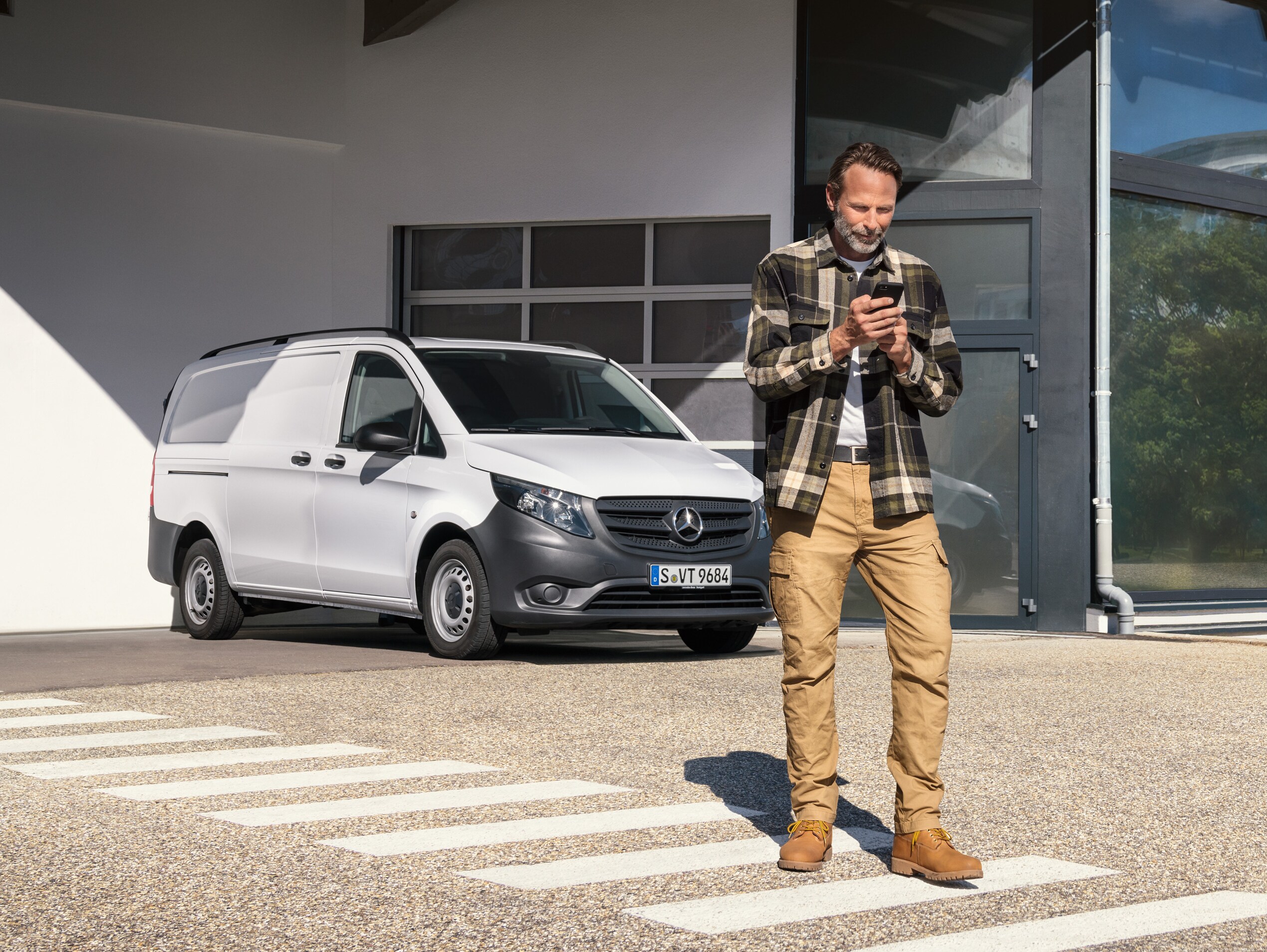 En man står framför en vit Mercedes-Benz Vito.