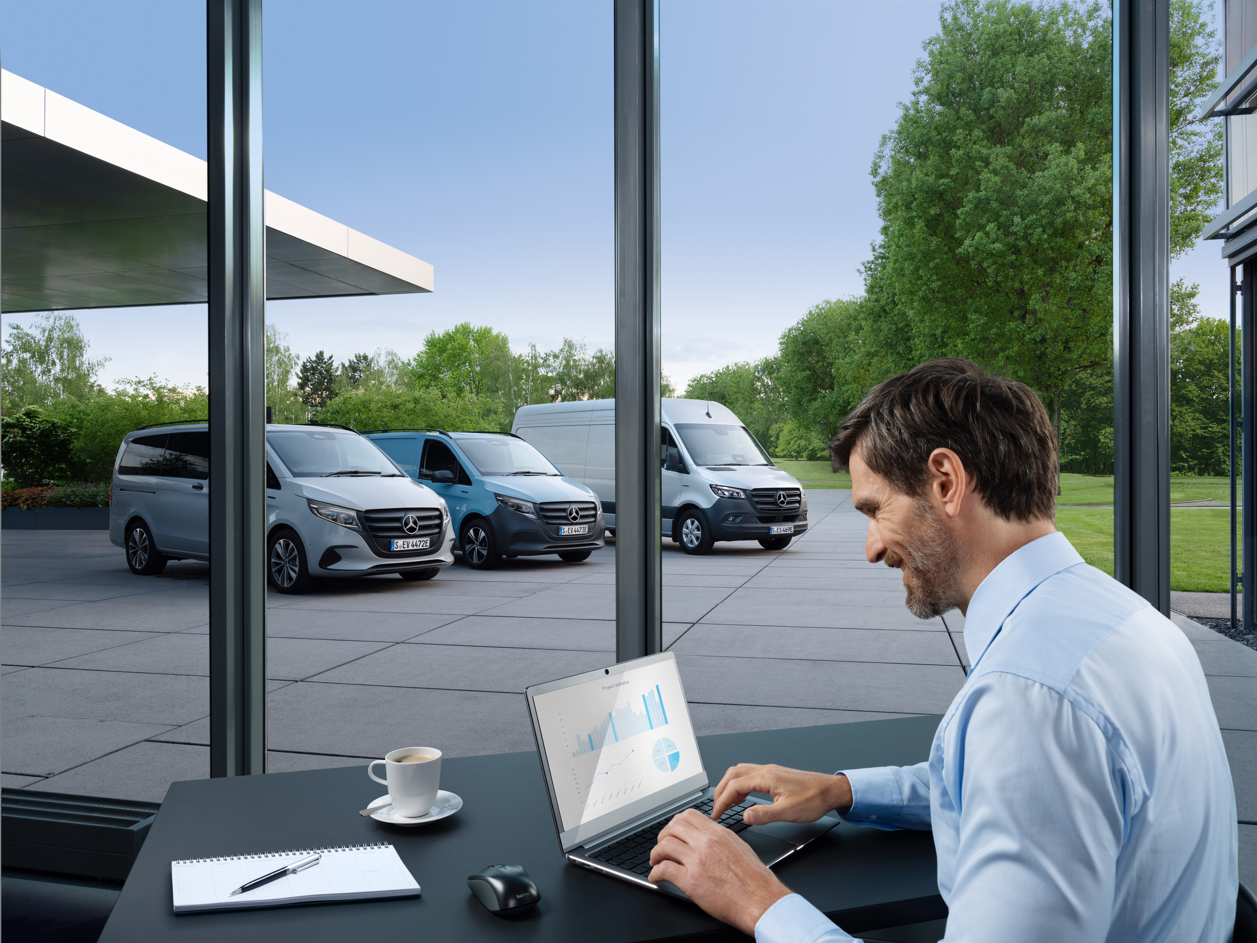 Mercedes-Benz | Service av elbilar | Paket Man arbetar på en bärbar dator, utanför står en rad Mercedes-Benz transportbilar.