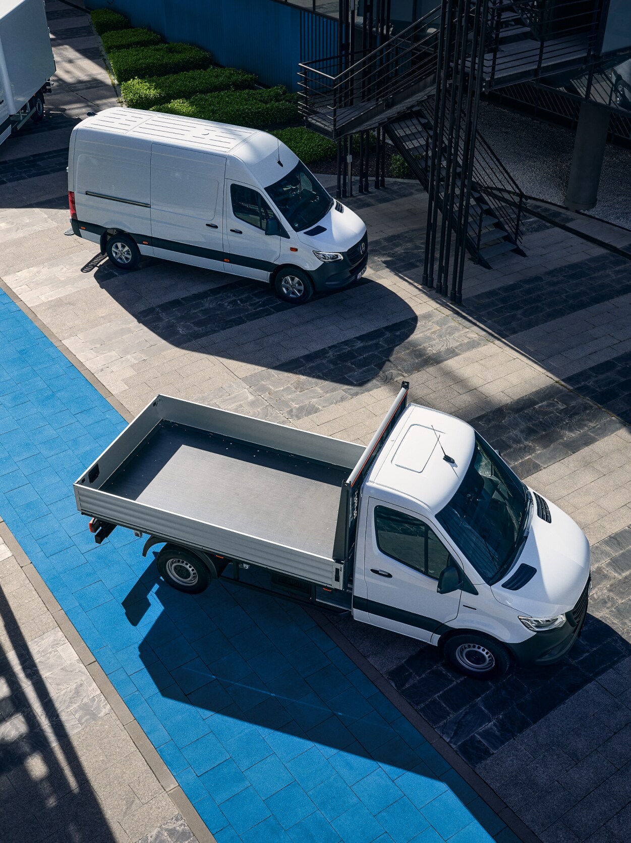 Tre vita Mercedes-Benz eSprinter står parkerade vid laddstolpe