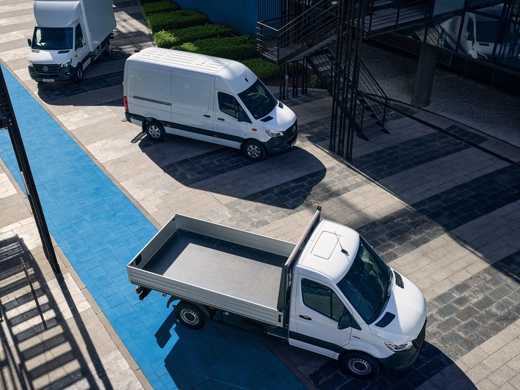 Tre vita Mercedes-Benz eSprinter står parkerade vid laddstolpe