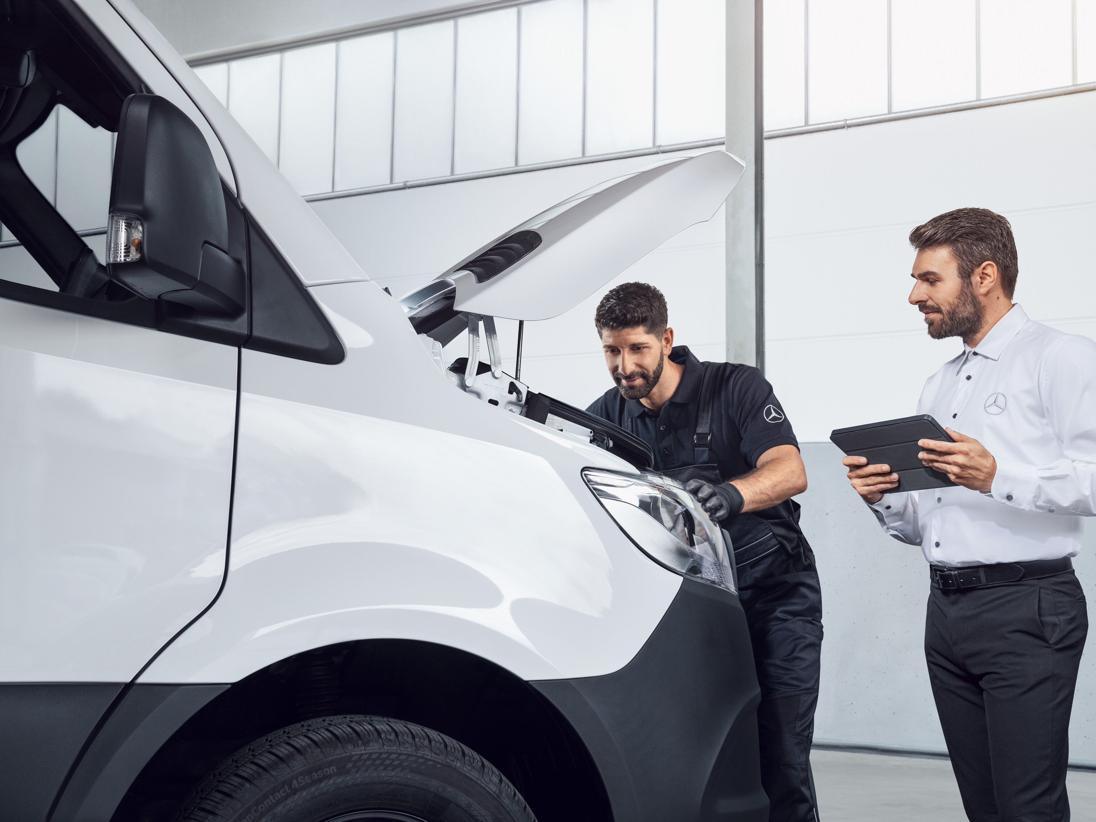 En Mercedes-Benz-mekaniker håller i en surfplatta och är redo att rapportera skador.
