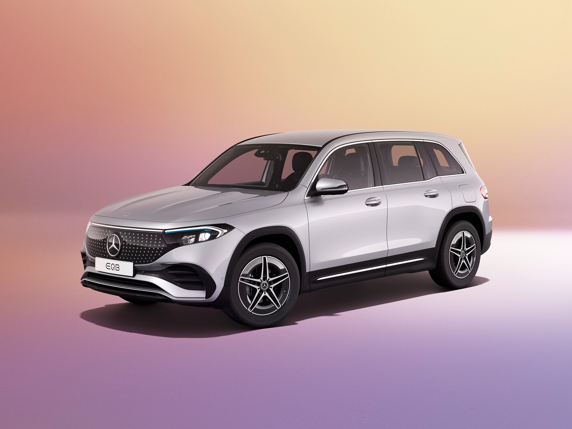 En Grå Mercedes-Benz EQB SUV sedd från sidan mot färgglad bakgrund.