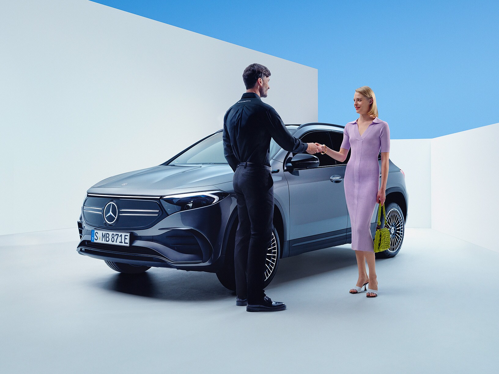 Kvinna tar emot bilnycklar från en Mercedes-Benz servicemedarbetare