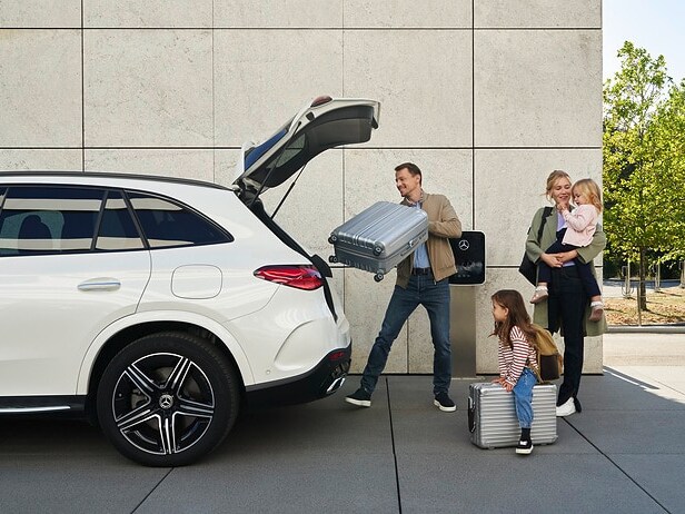 Familj packar väskor i bagageutrymmet på en Mercedes-Benz-bil