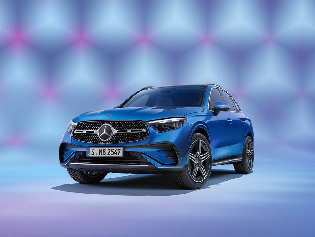 En blå Mercedes-Benz GLC SUV sedd framifrån mot färgglad bakgrund.