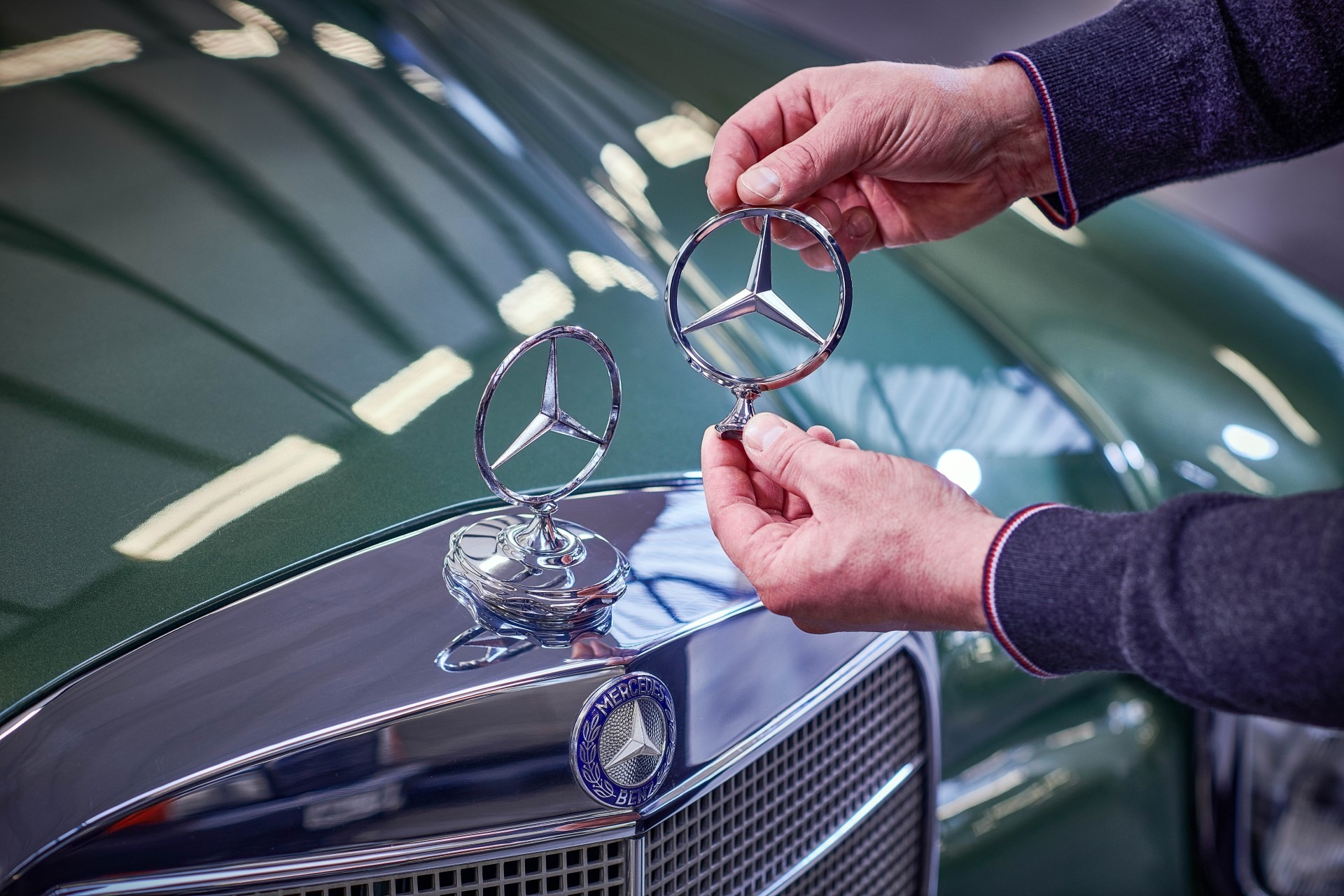 Mercedes-Benz Classic | Mercedes-Benz En man jämför Mercedes-stjärnor på en klassisk Mercedes-Benz.