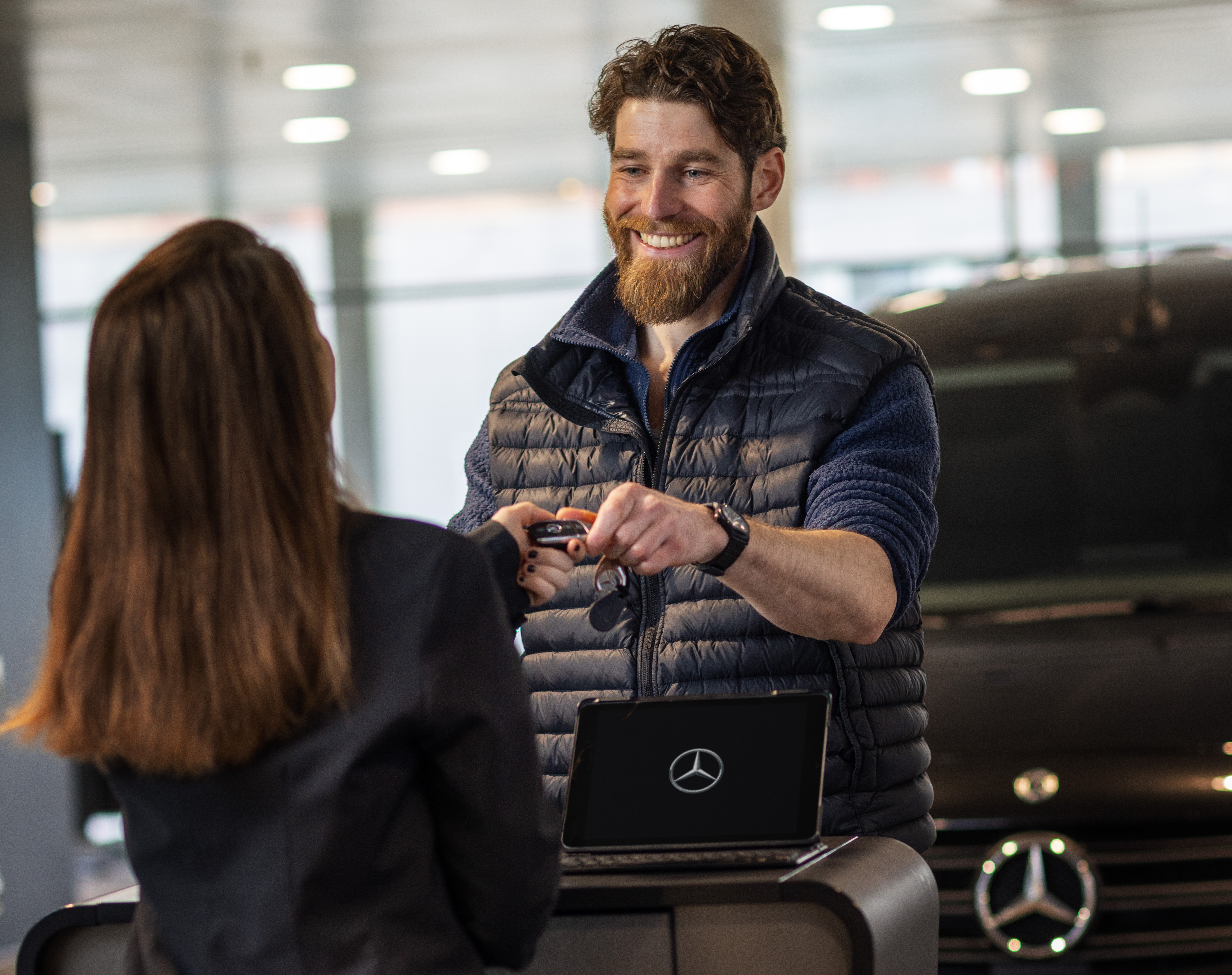 Leasa en 7-sitsig elbil | 7-sitsiga elbilar för familjen | Mercedes-Benz Man får bilnyckel av Mercedes-Benz medarbetare