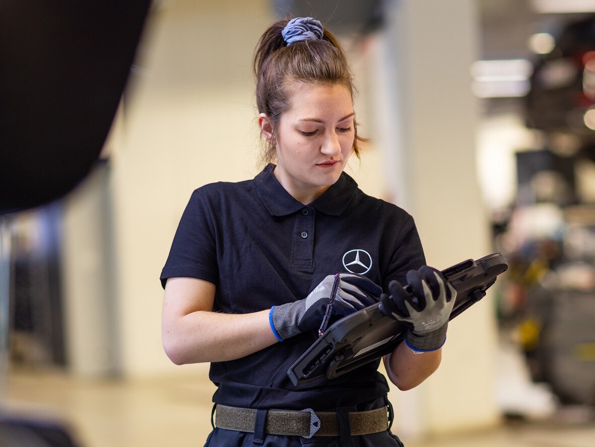 En Mercedes-Benz mekaniker i svart skjorta håller en laptop i sina händer
