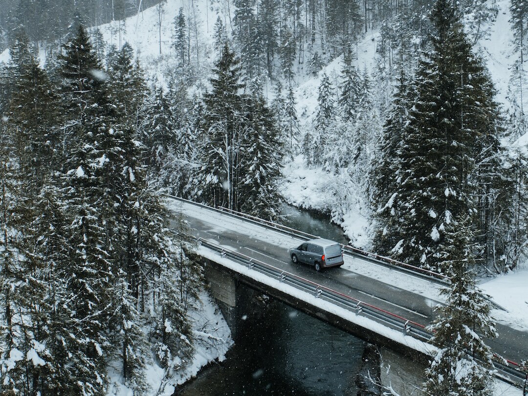 En Mercedes-Benz transportbil kör genom en snötäckt bergspassage.