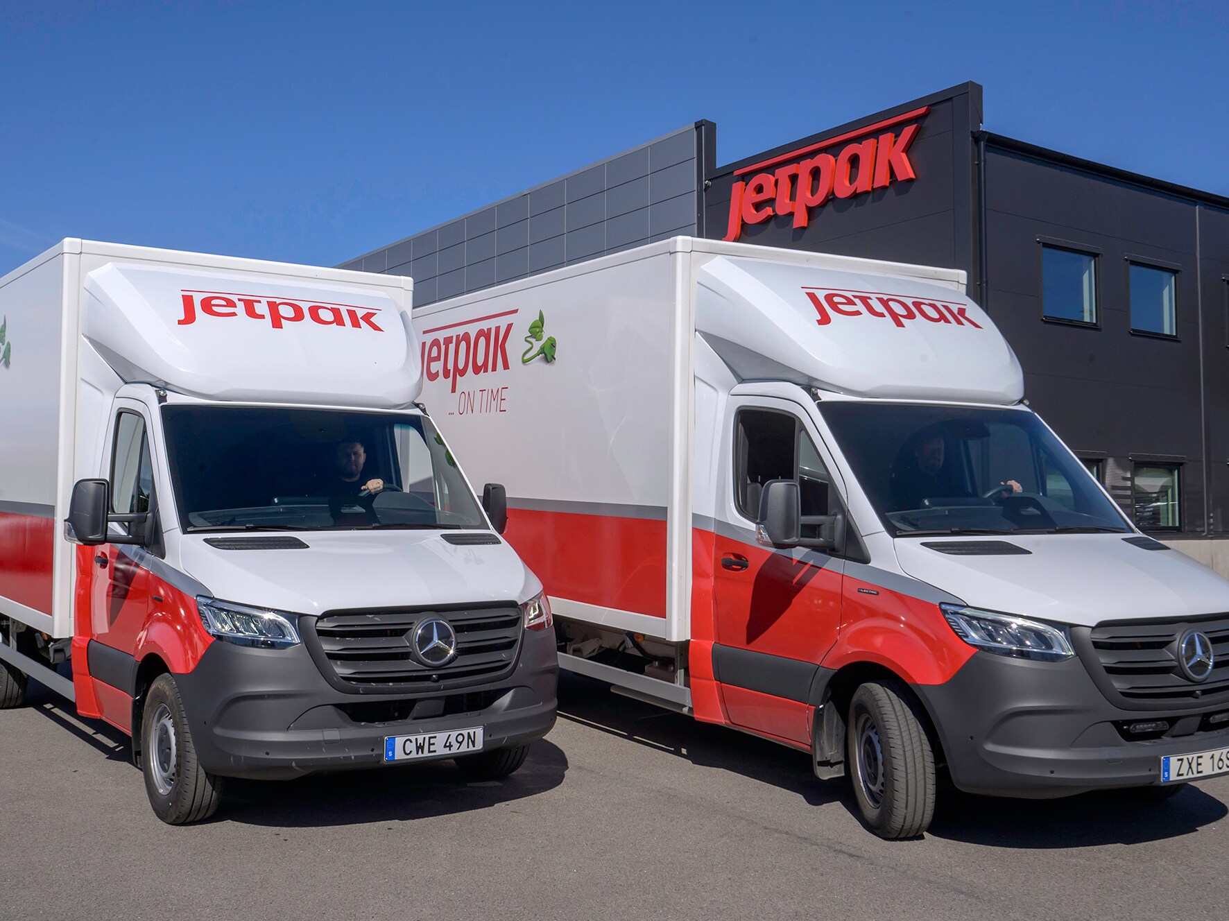 Person står framför två vita Mercedes-Benz eSprinter från Jetpak