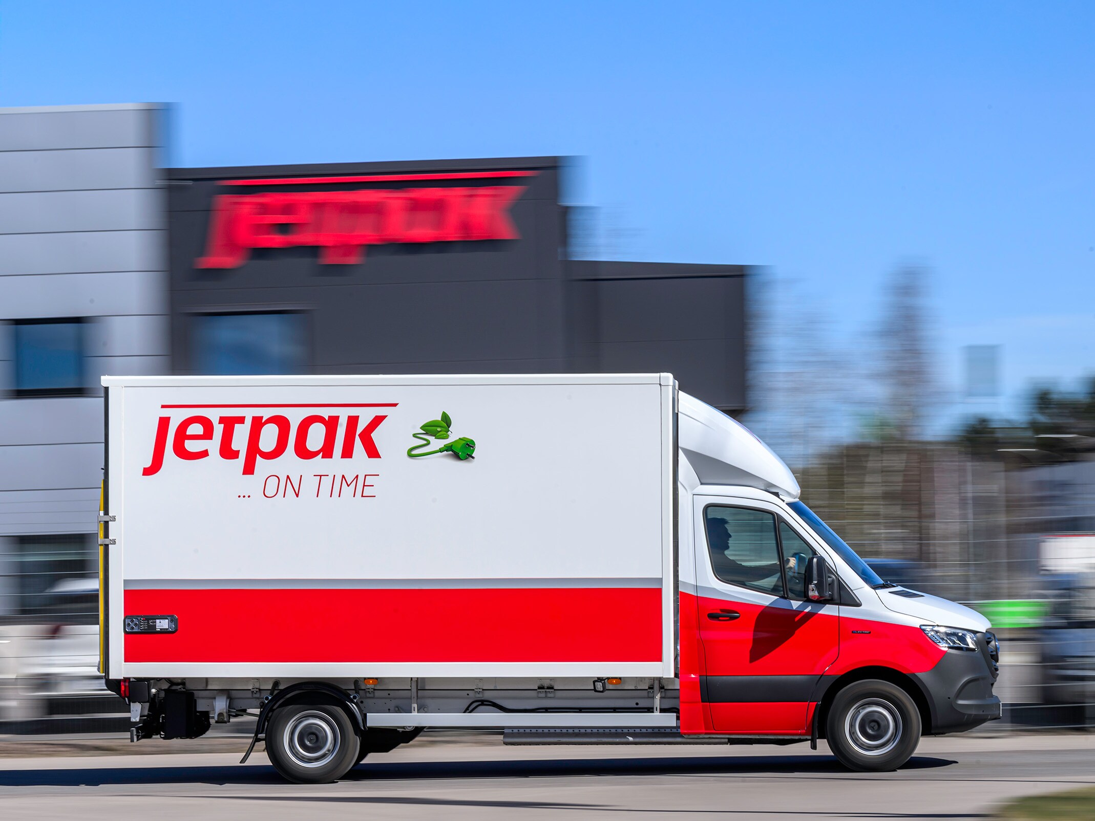 Person står framför två vita Mercedes-Benz eSprinter från Jetpak