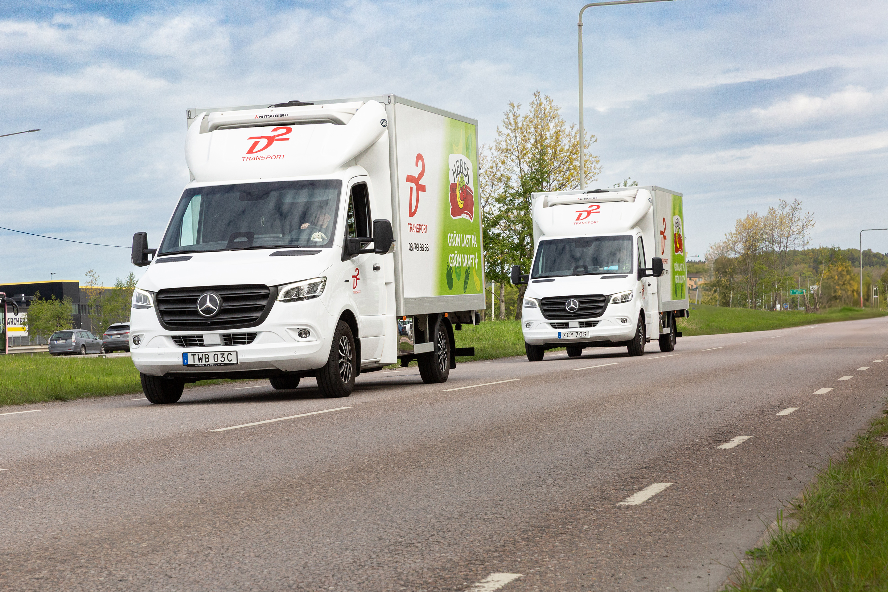 D2 Transport | Mercedes-Benz Transportbilar Två vita eldrivna transportbilar eSprinter från Mercedes-Benz kör på landsväg