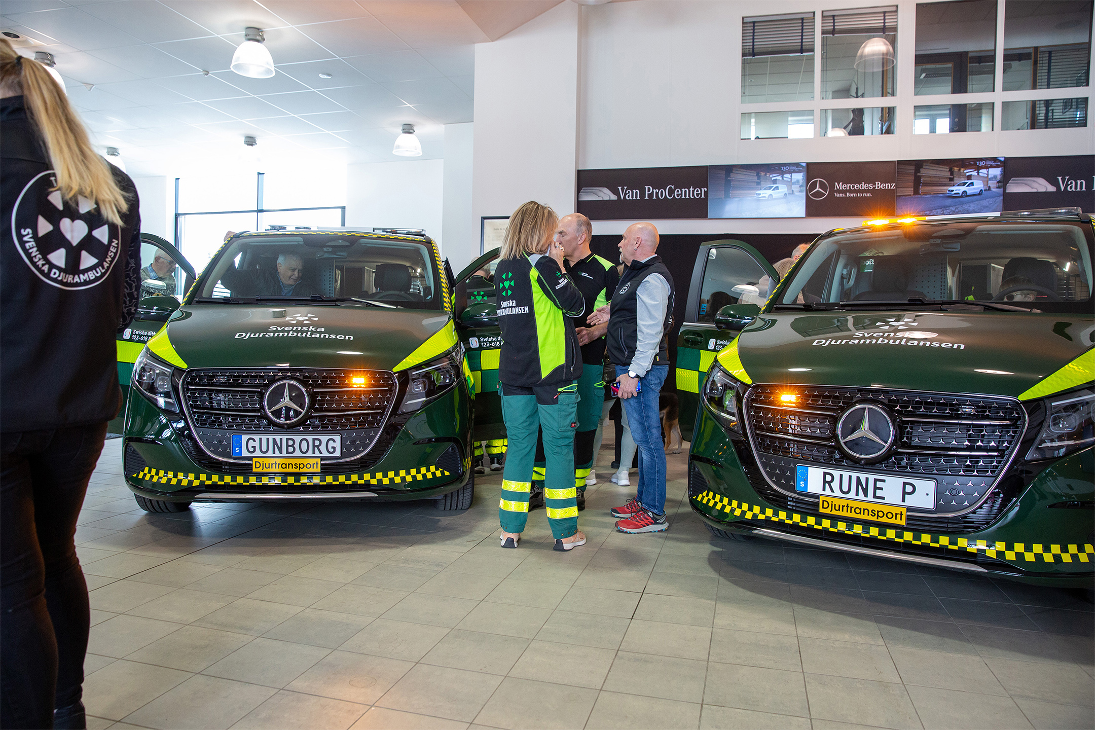 Djurambulans | Mercedes-Benz Transportbilar Två räddningsfordon med blåljus i bilhall; folk samtalar.