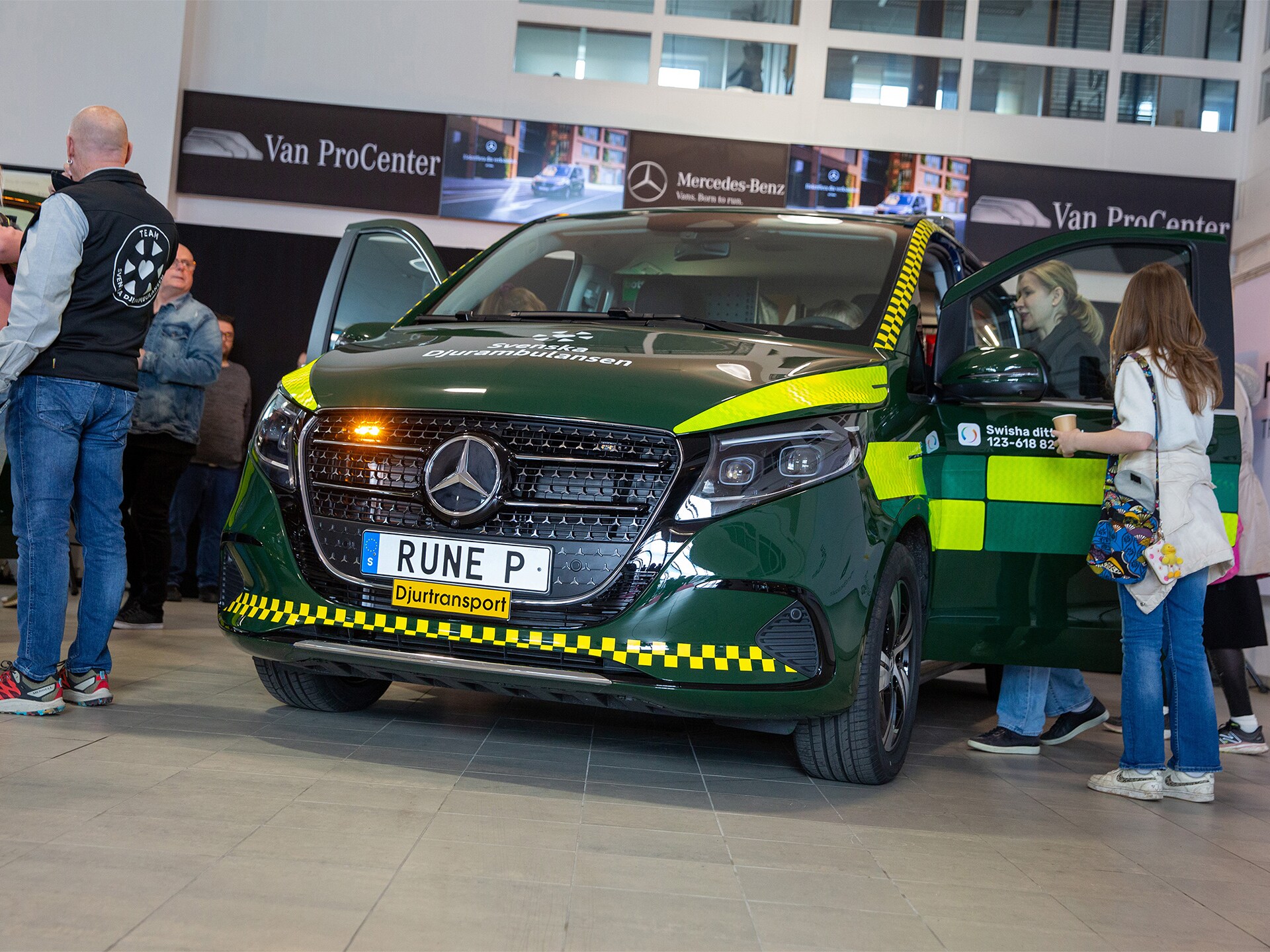 Grön Mercedes-Benz ambulansbil på mässa med öppna dörrar.