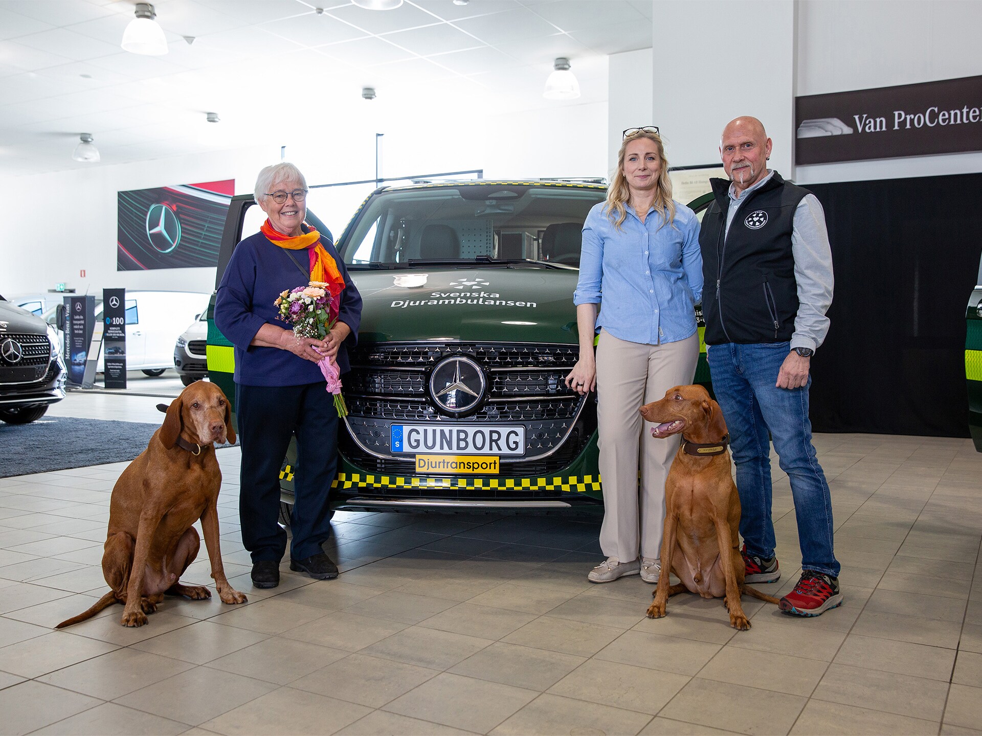 Tre personer och två hundar framför en djurambulans.