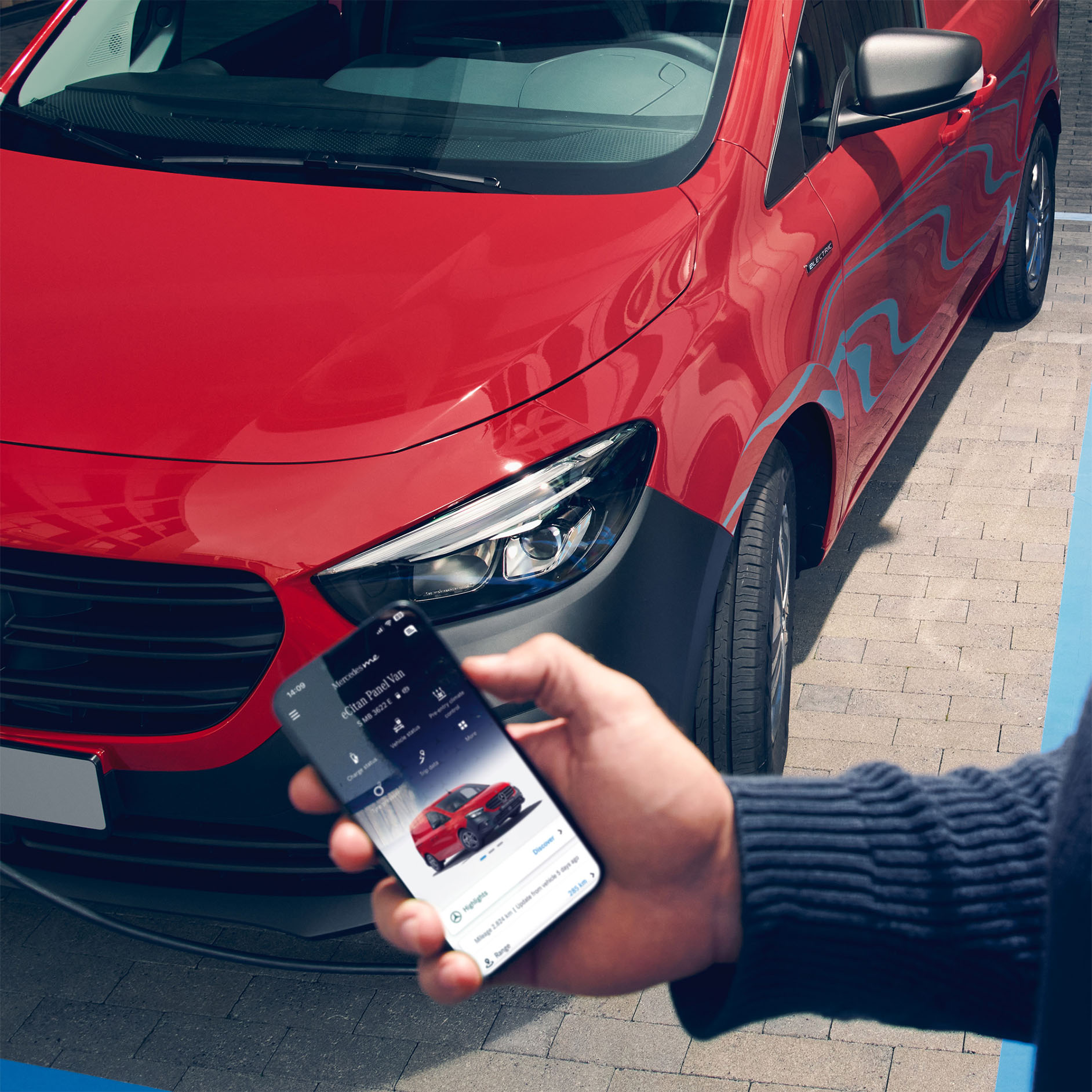 Leasa helelektriska eCitan | Mercedes-Benz Transportbilar Person håller smartphone med Mercedes-Benz-appen öppen, eCitan i bakgrunden