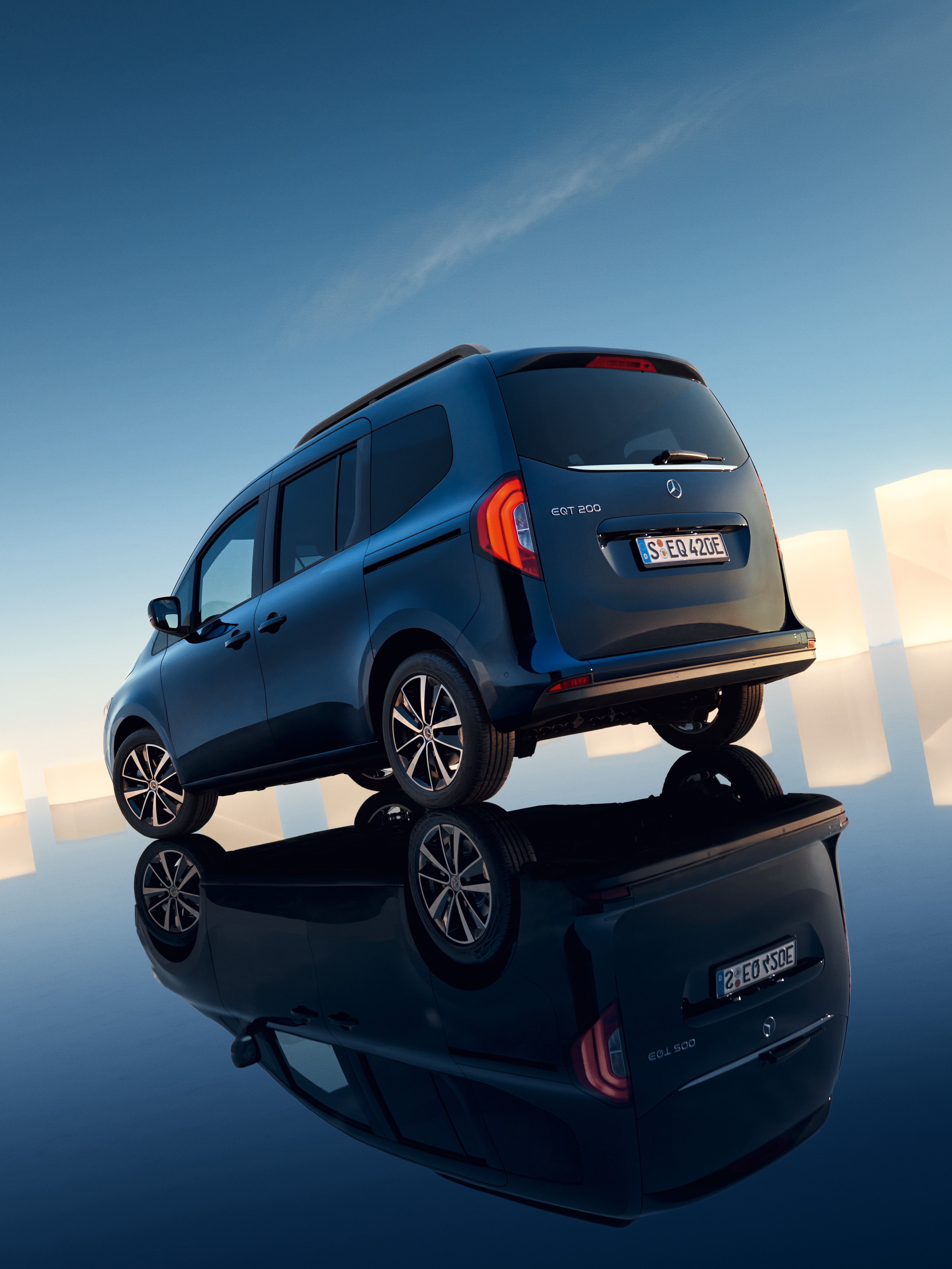 En blå Mercedes-Benz EQT står parkerad på spegelblank yta