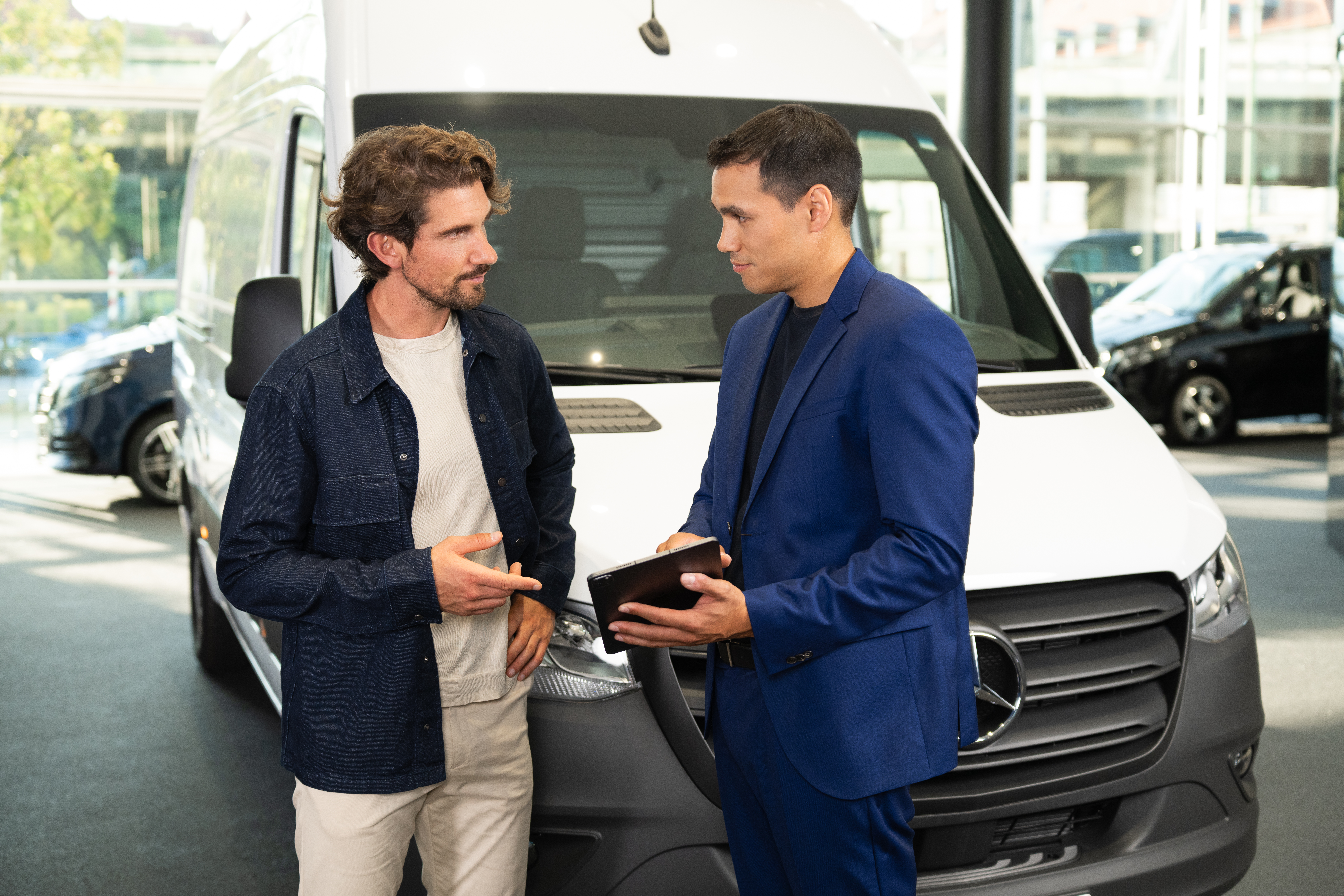 Återvinning av uttjänta fordon | Mercedes-Benz Transportbilar Man pratar med Mercedes-Benz-återförsäljare i showroom.